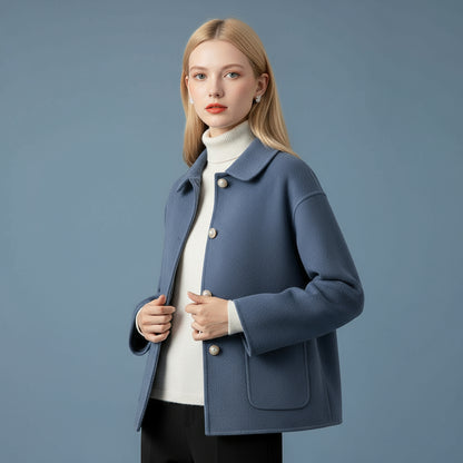 Woman wearing a blue coat over a white sweater on a blue background