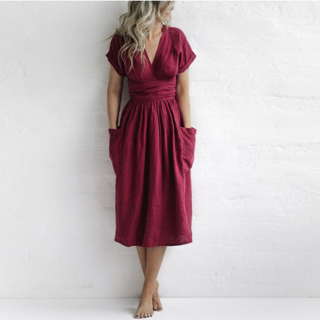 Woman wearing a burgundy dress with short sleeves and pockets on a white background