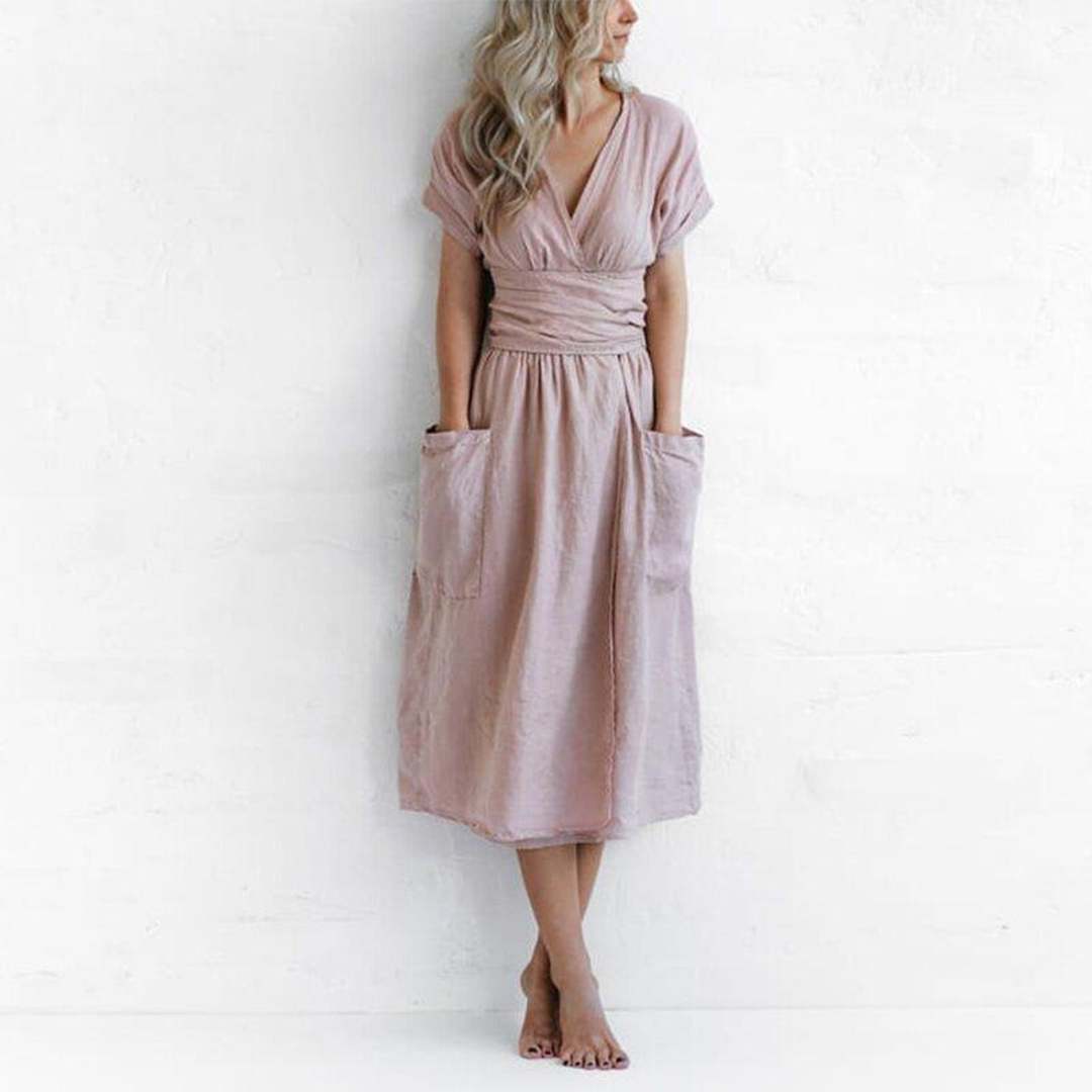 Woman wearing a pink dress with pockets against a white background
