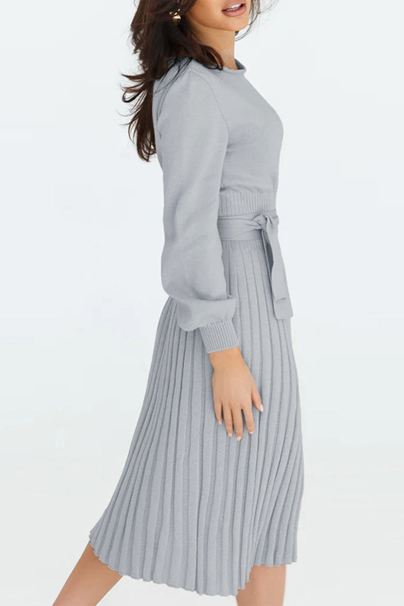 Woman wearing a gray sweater and pleated skirt on a white background