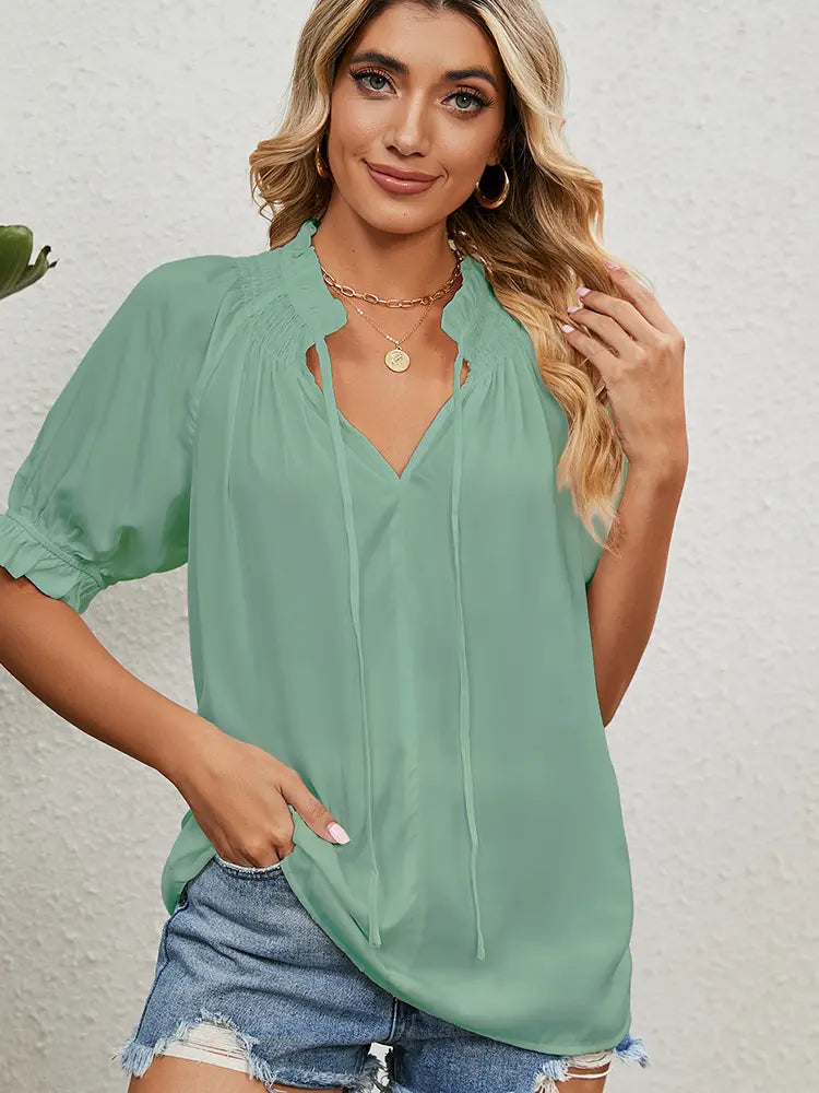 Woman wearing a light green blouse with a plain background