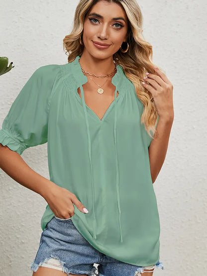 Woman wearing a light green blouse with a plain background