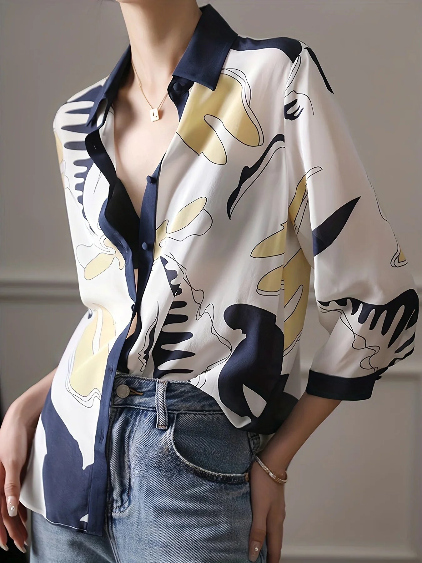 Person wearing a patterned shirt with abstract designs in white, black, and yellow, paired with blue jeans.